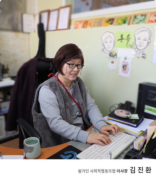 쉴가인 김진환 이사장님이 책상에 앉아서 서류에 싸인을 하시는 모습의 사진입니다. 